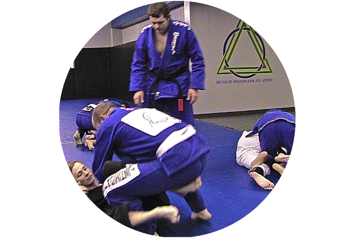 Coach, Max Burt, instructing a small group practicing brazilian jiu jitsu